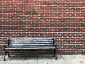 Grey Wooden bench beside brown wall By Elisabeth Lee from Unsplash